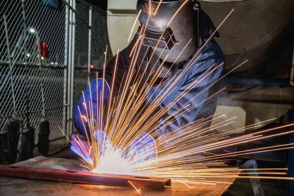 A Man Is Welding A Piece Of Metal In A Factory — Agriweld Engineering in Dubbo, NSW