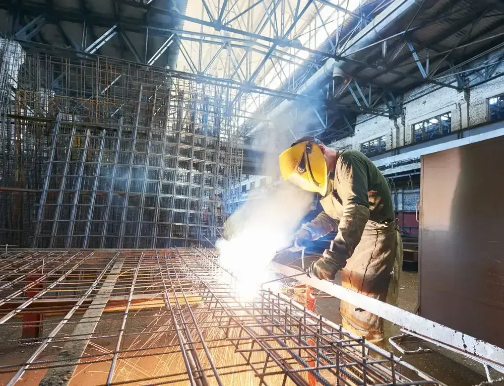 A Man Is Welding A Metal Structure In A Factory — Agriweld Engineering in Dubbo, NSW