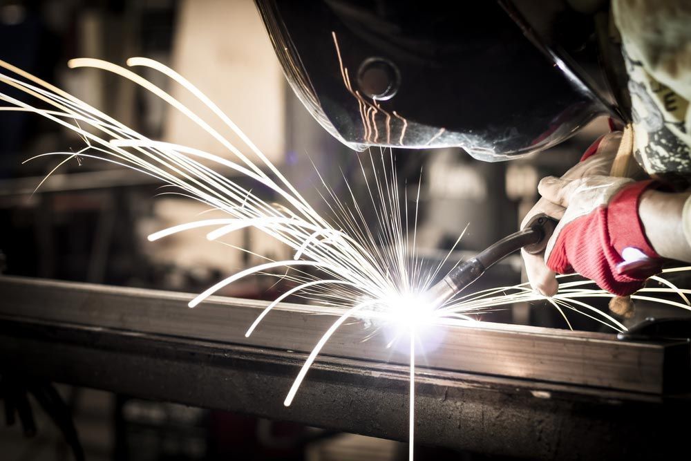 A Man Is Welding A Piece Of Metal In A Factory — Agriweld Engineering in Dubbo, NSW