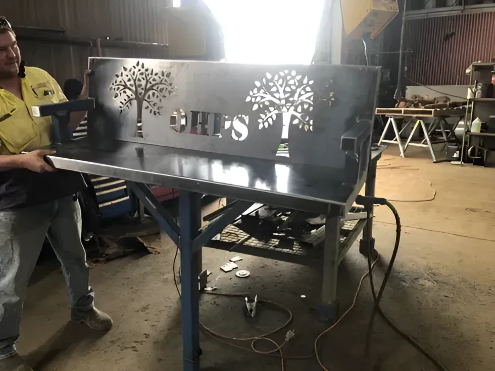 A Man Is Standing Next To A Metal Table With A Tree On It — Agriweld Engineering in Dubbo, NSW