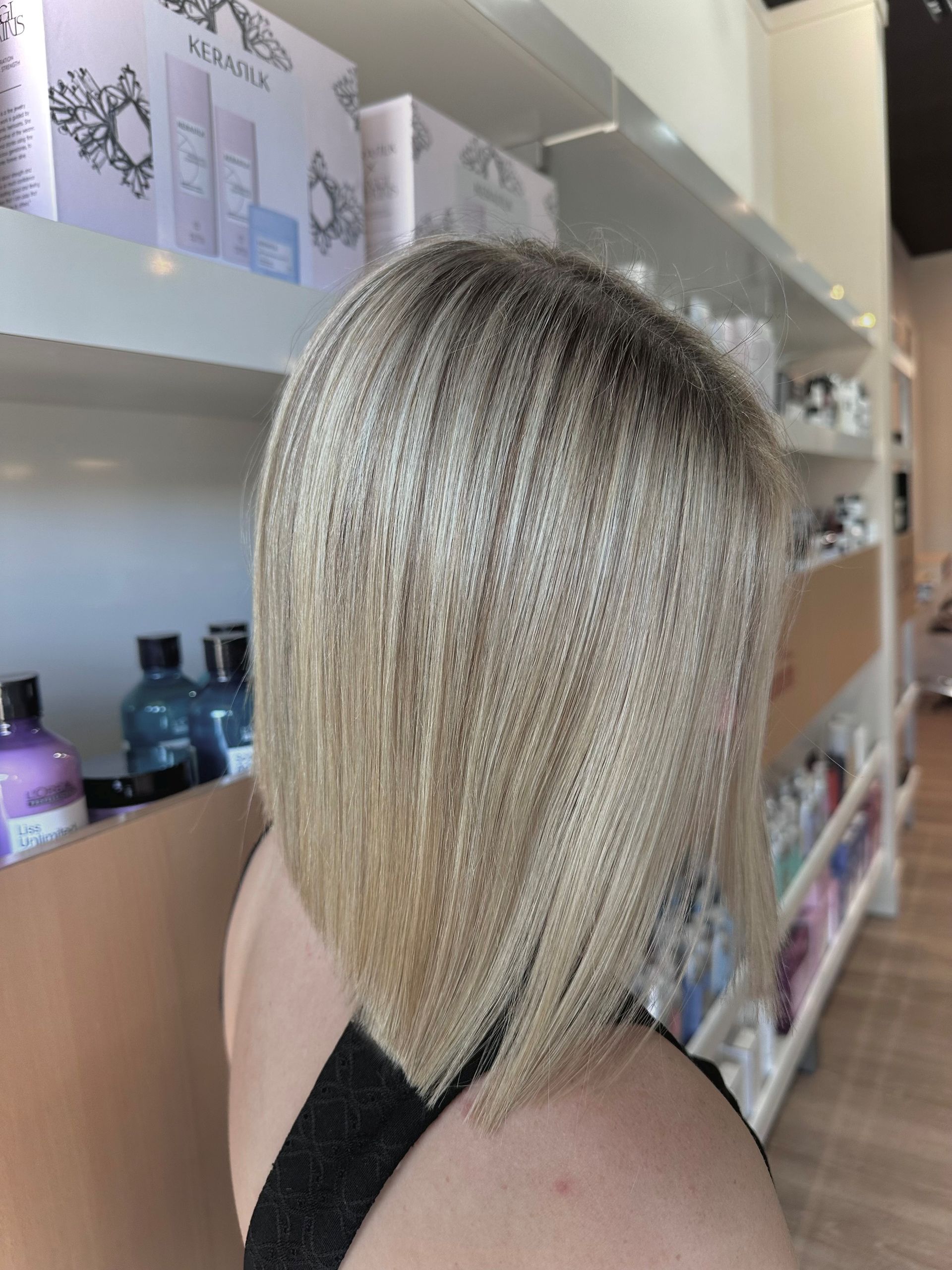 Woman With Long, Wavy, Blonde Hair At A Salon, Wearing A Black Smock — Gina T Hair & Beauty In Mackay, QLD