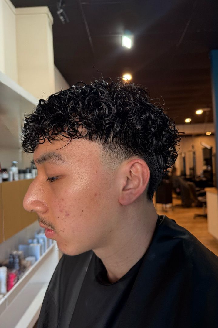 Man with curly black hair, low fade haircut. He’s in a salon.— Gina T Hair & Beauty In Mackay, QLD