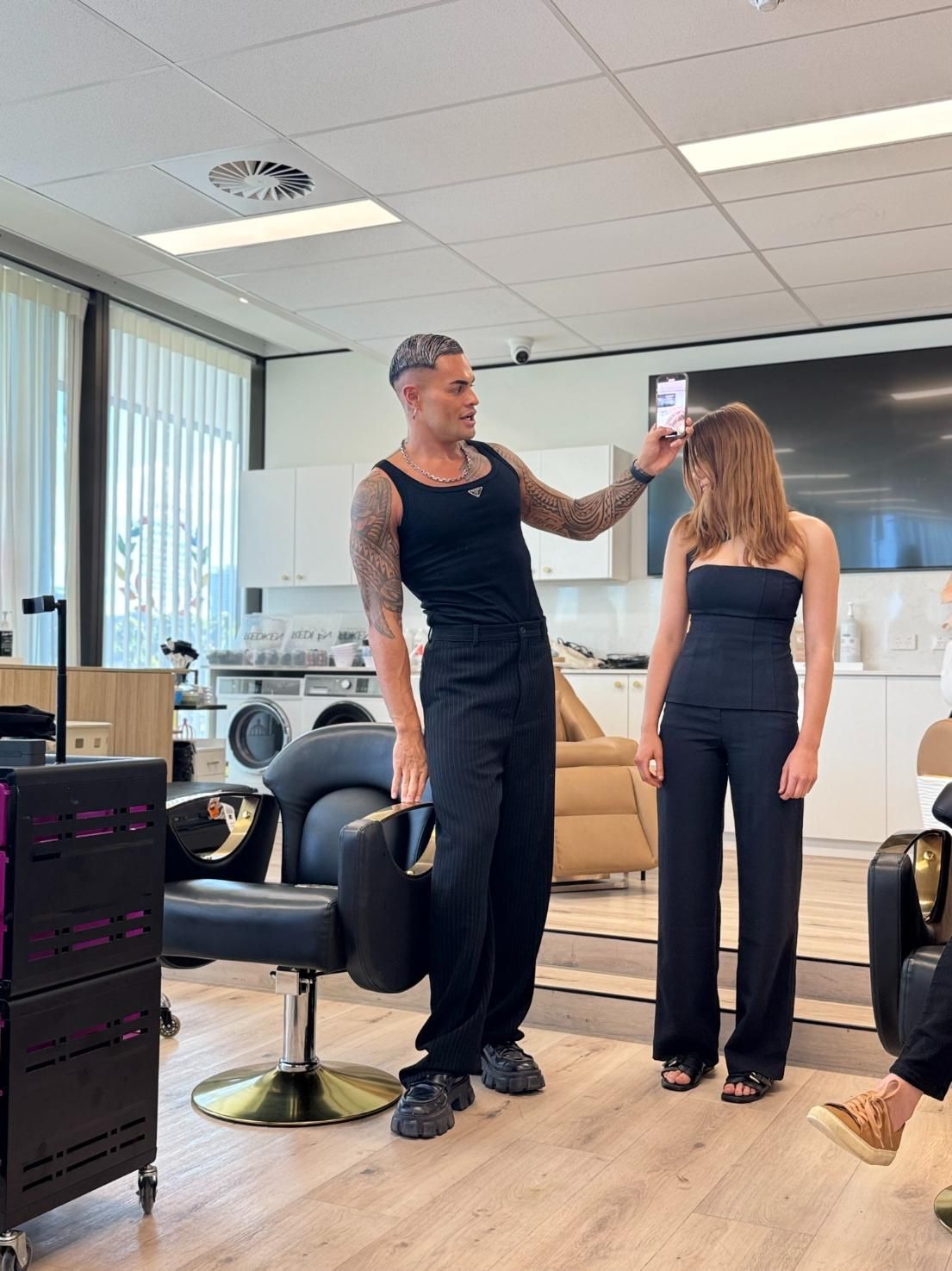 Hairdresser Taking a Photo of a Woman in a Salon. Man With Tattoos, Dark Clothes — Gina T Hair & Beauty In Mackay, QLD