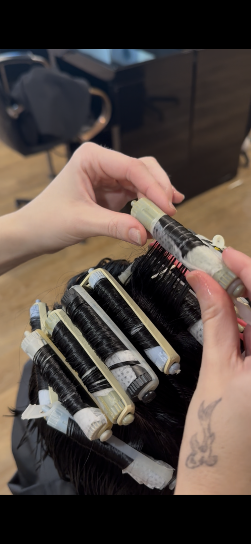 Hands rolling hair around perm rods in a salon.— Gina T Hair & Beauty In Mackay, QLD