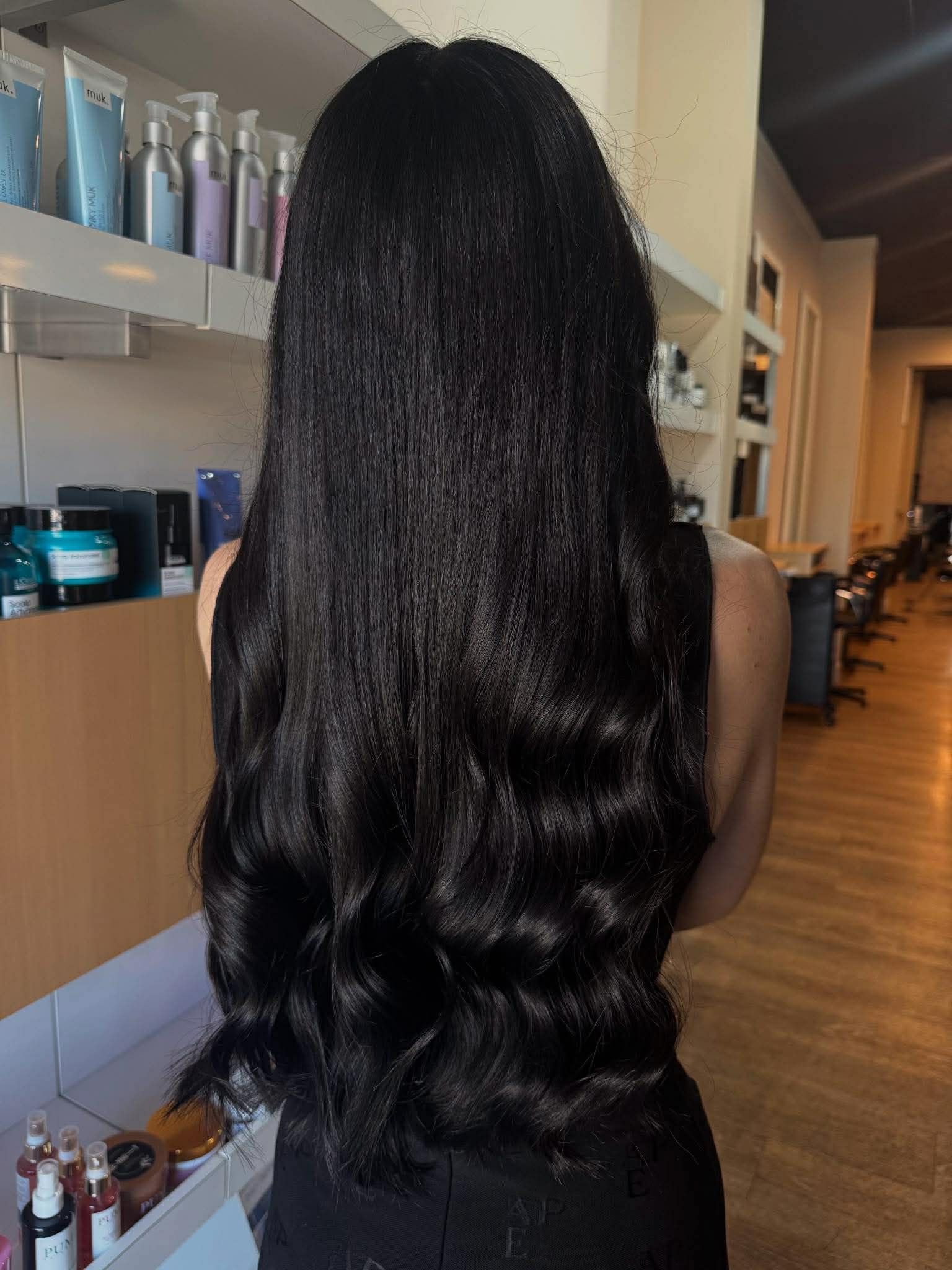 A Young Woman With Long, Straight Platinum Blonde Hair Stands Inside A Beauty Salon — Gina T Hair & Beauty In Mackay, QLD