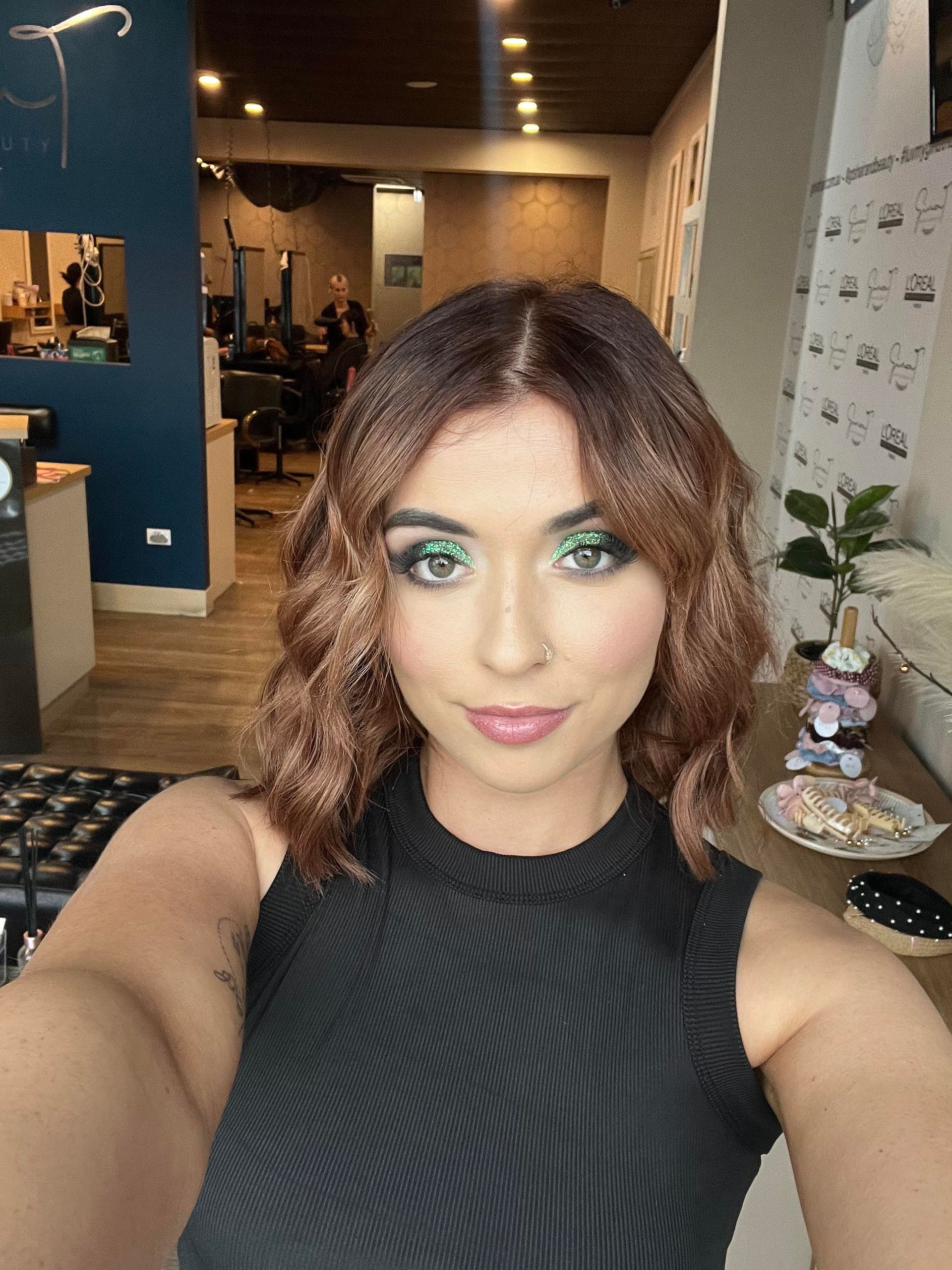 Woman With Wavy Auburn Hair And Green Eye Makeup Takes A Selfie In A Salon — Gina T Hair & Beauty In Mackay, QLD
