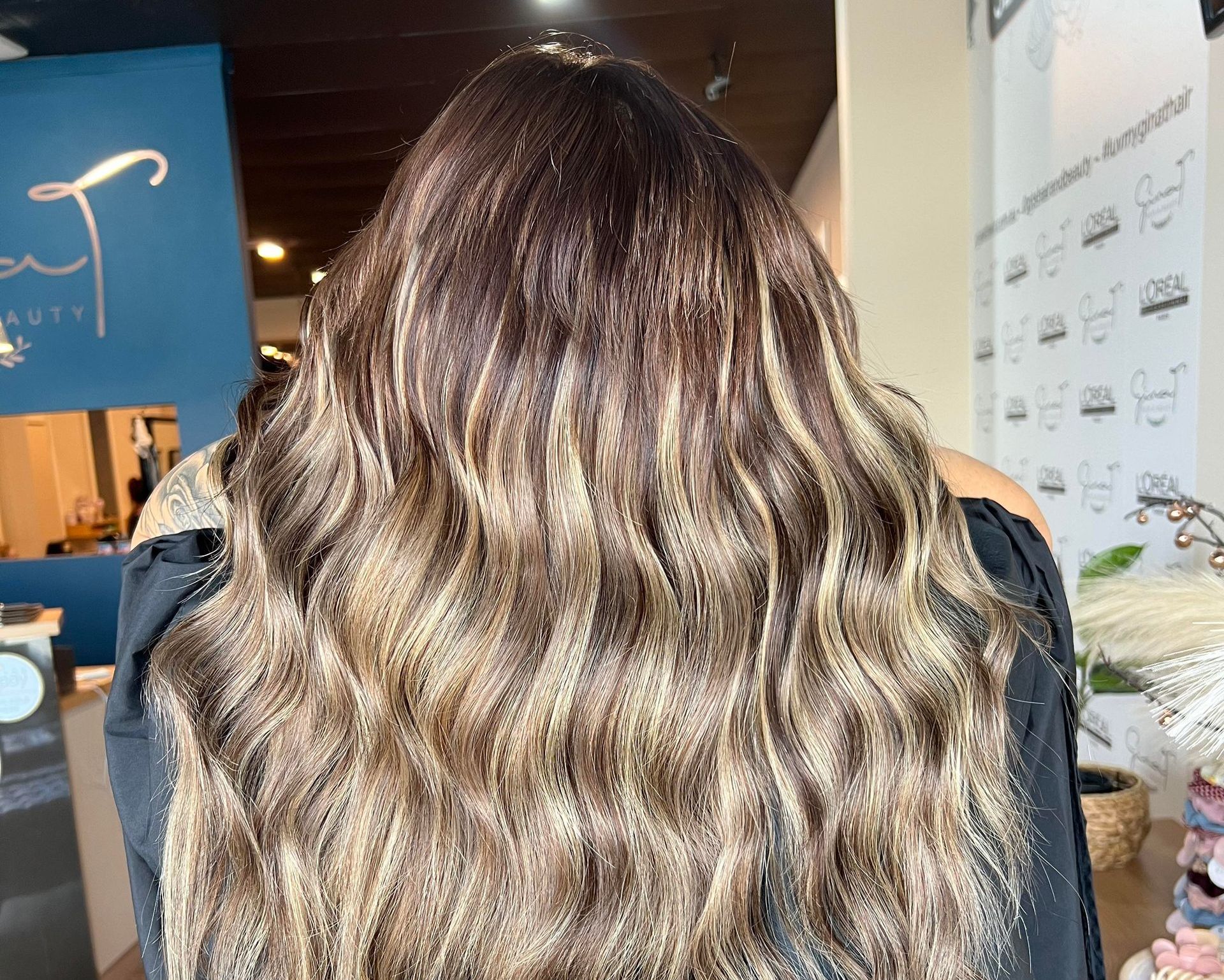 Woman With Wavy, Brown Hair And Highlights, Wearing A Teal Top — Gina T Hair & Beauty In Mackay, QLD