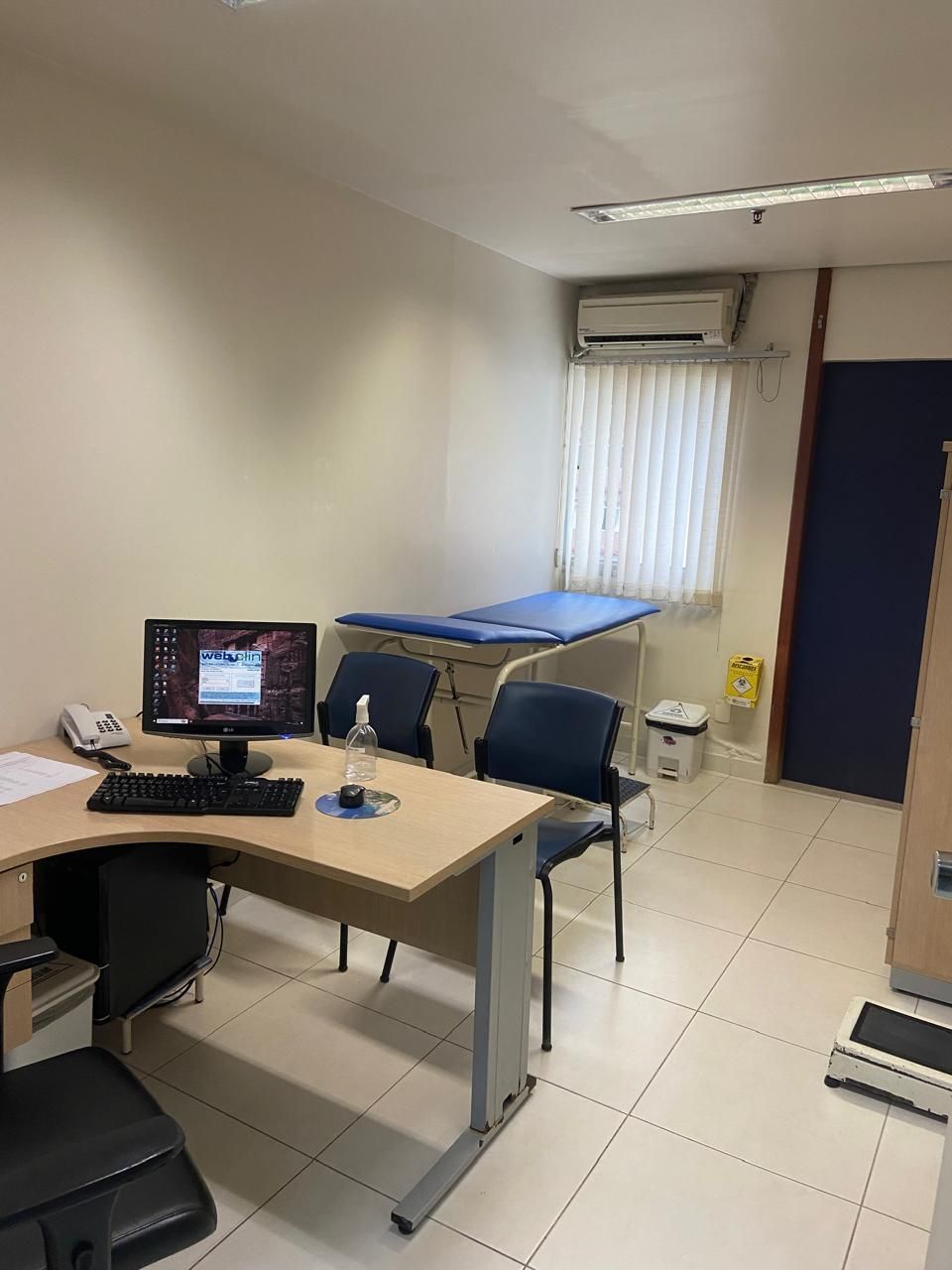 Um consultório médico com uma mesa, cadeiras e um computador.