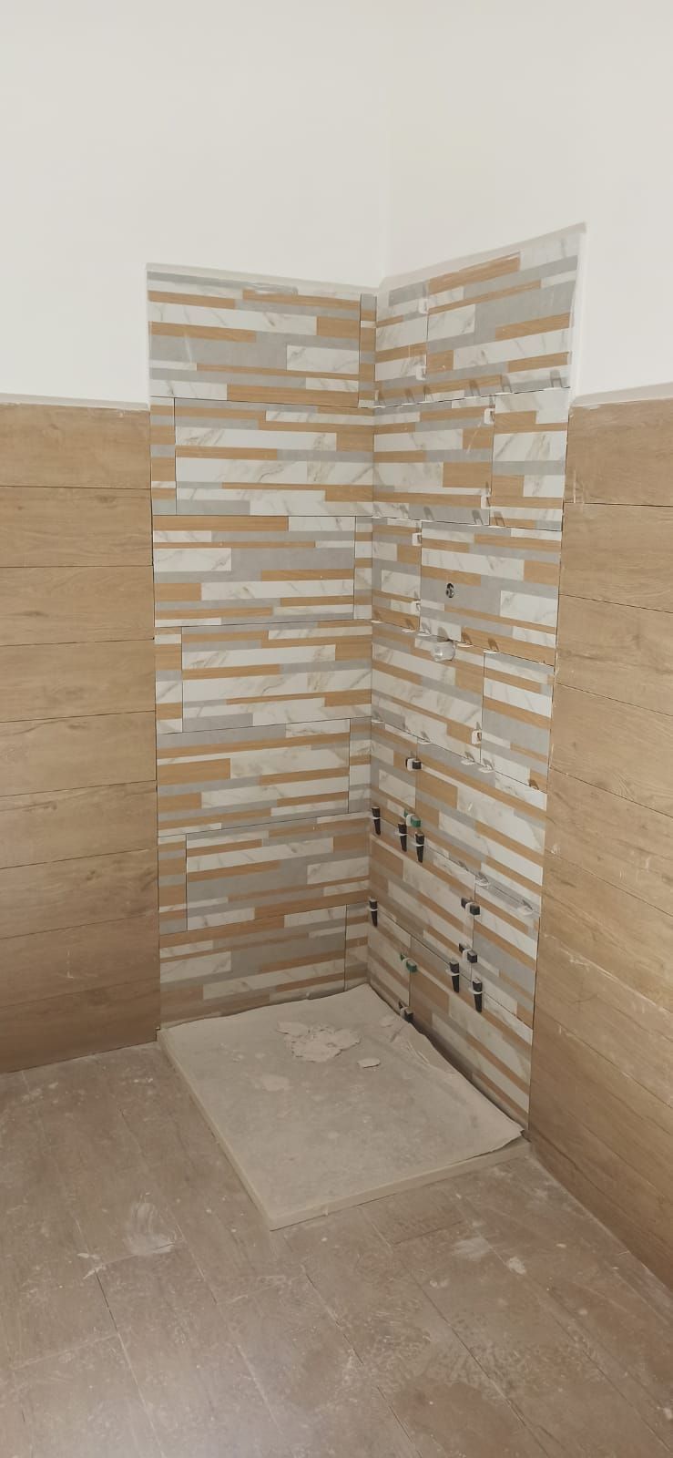 Uomo con equipaggiamento di sicurezza che si cala in corda doppia da un edificio, casco verde, attrezzatura in mano, vista dall'alto.