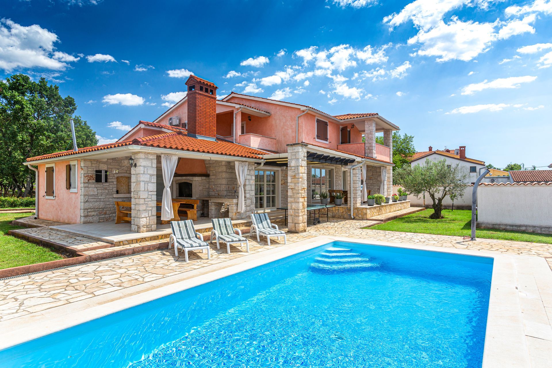 A house and a cottage with a pool surrounded by green foliage. A house and a cottage with a pool surrounded by green foliage.