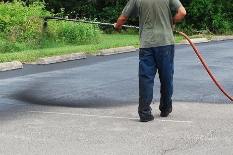 A machine is painting white lines on a parking lot.