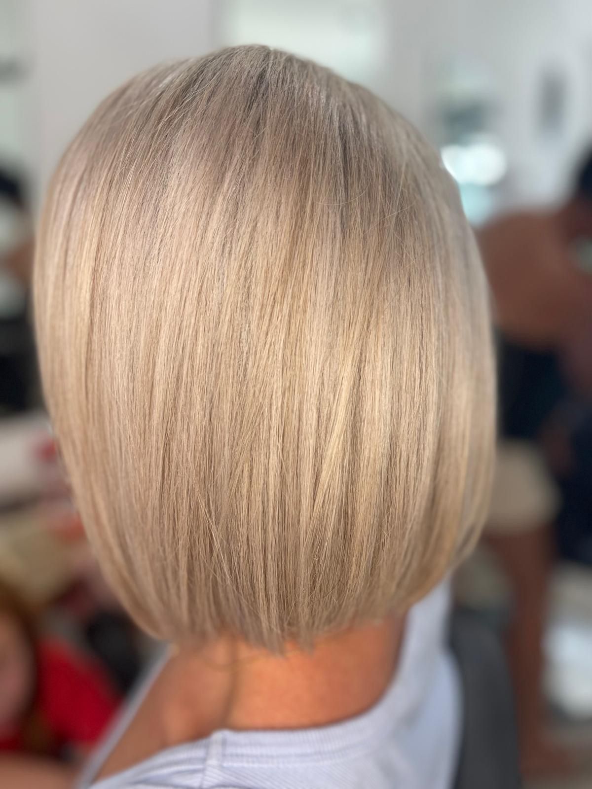 Short blonde bob haircut viewed from the back in a blurred indoor setting