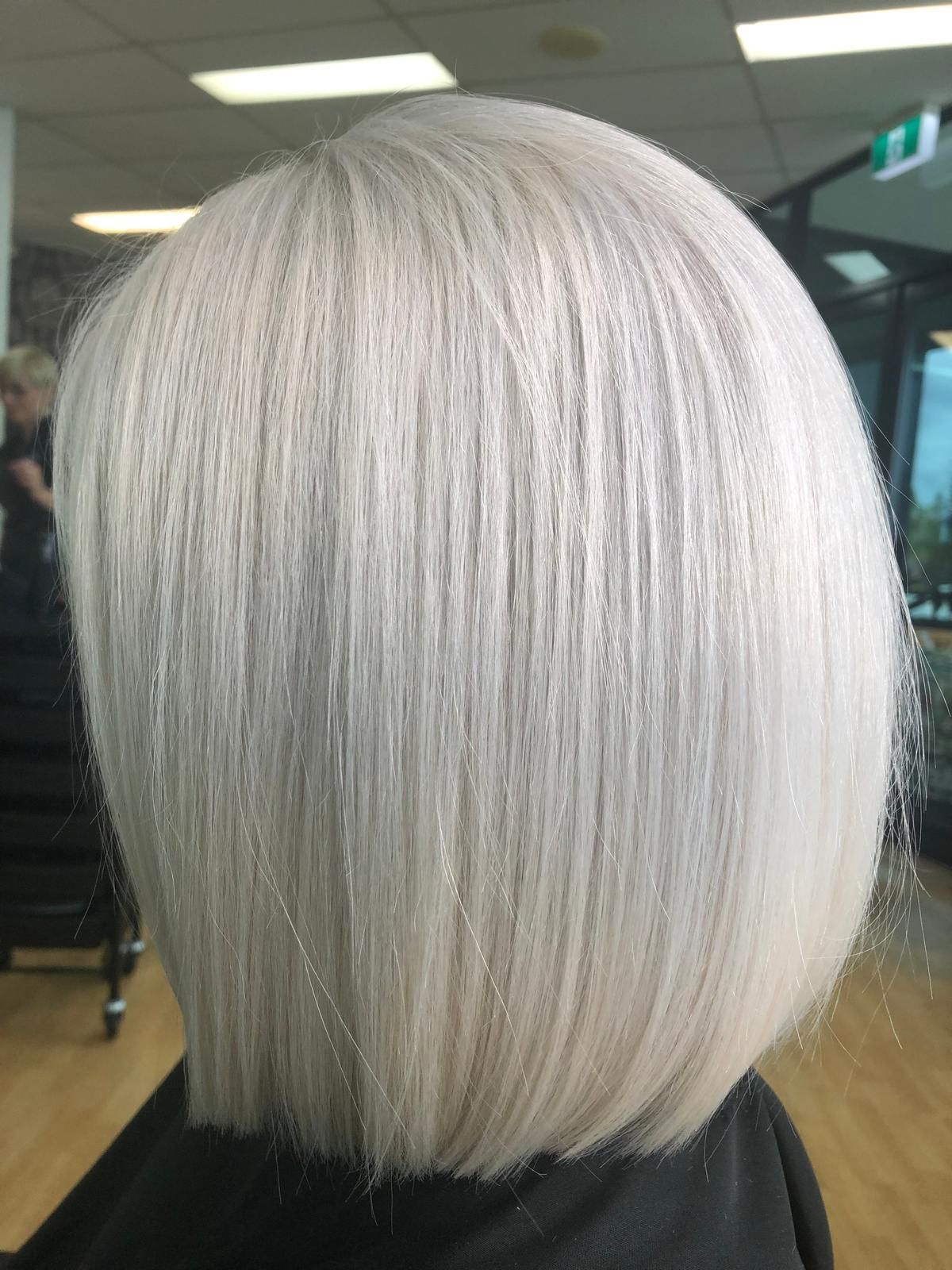 Short platinum-blonde bob haircut shown from the back in a salon chair