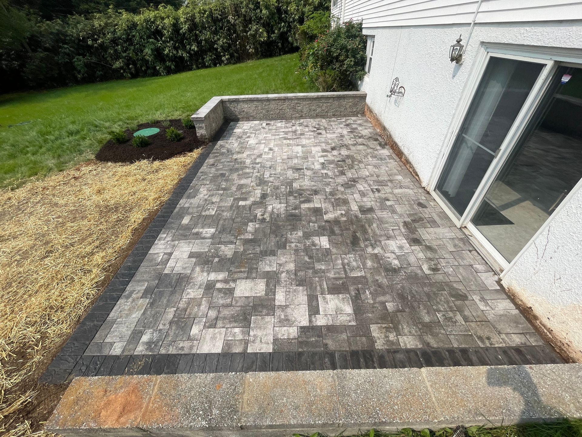 A patio with a sliding glass door in the backyard of a house.