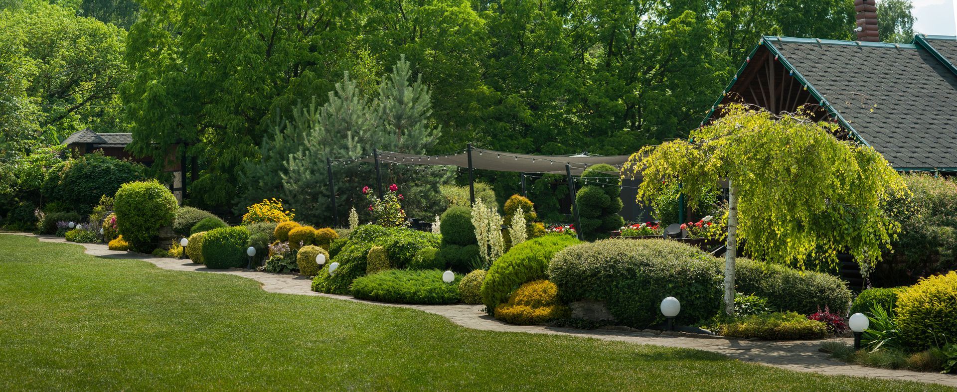 A yard filled with mulch and flowers with a house in the background.