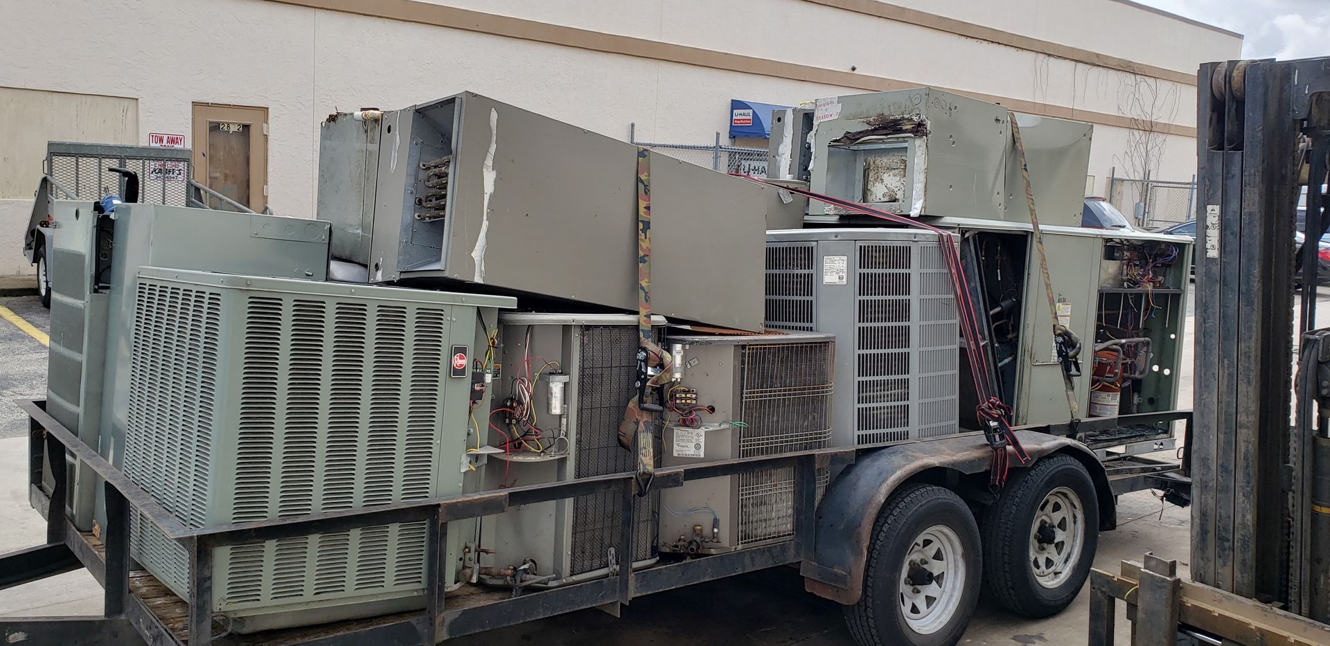 A trailer filled with a bunch of air conditioners and a forklift.