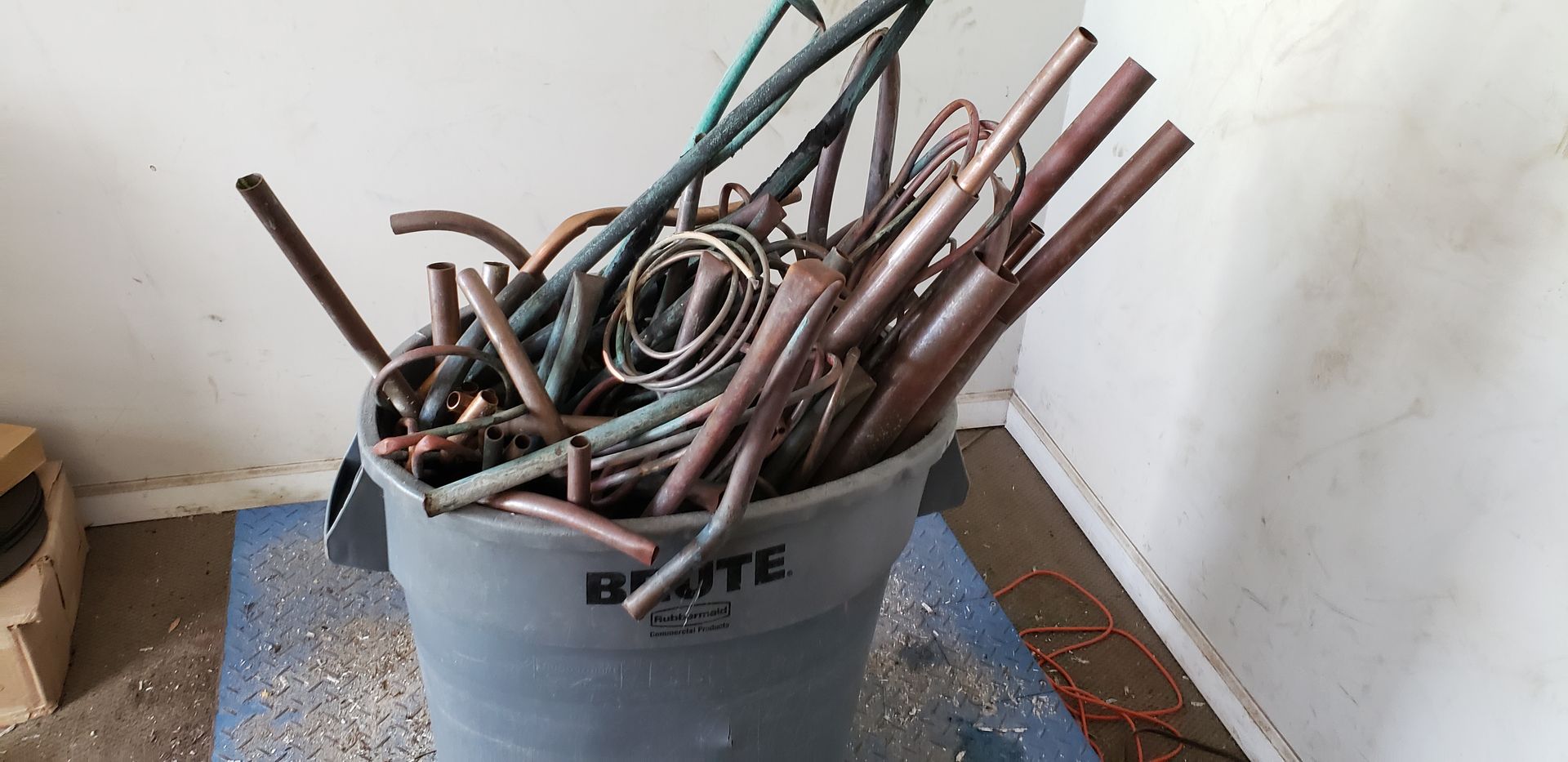 A bucket filled with copper pipes and wires is sitting on a table.