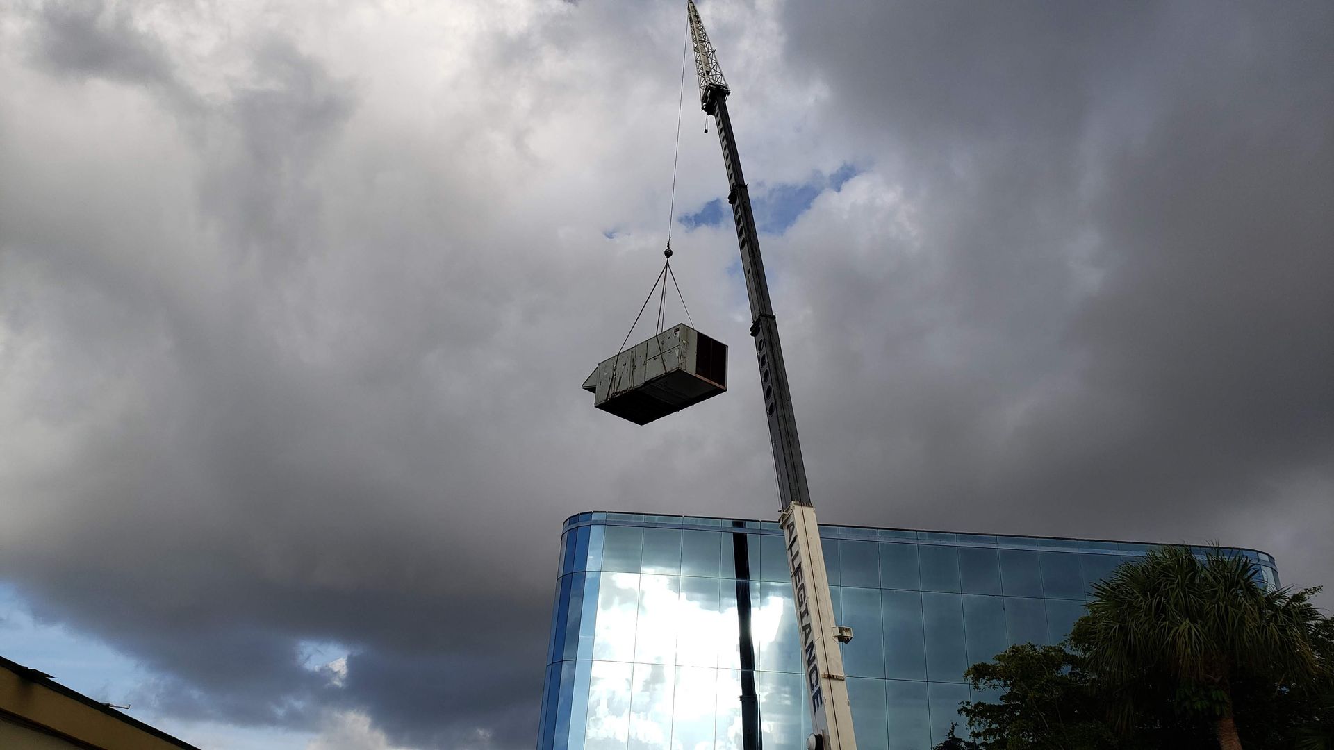 A crane is lifting a large box into the air over a building.