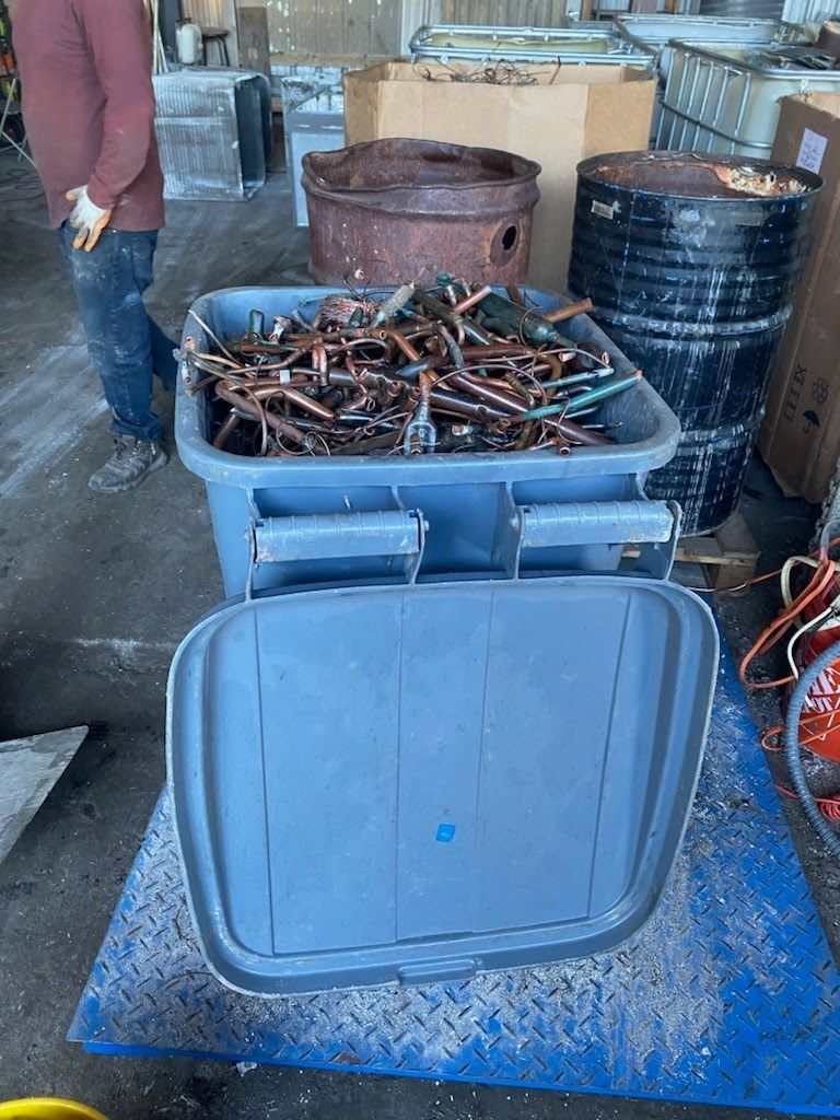 A trash can filled with copper is sitting on a scale.