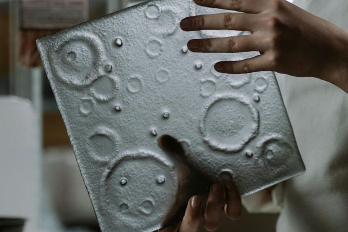 A person is holding a piece of glass with circles on it.