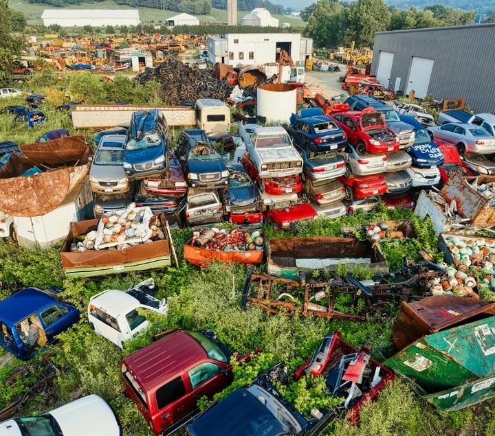 A bunch of cars are sitting on top of each other in a field.