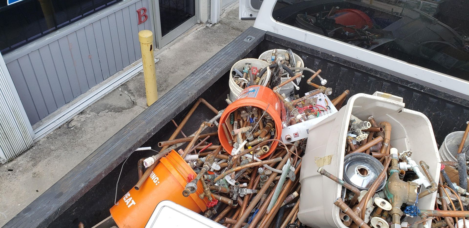 A truck bed filled with junk and a bucket that says home depot on it