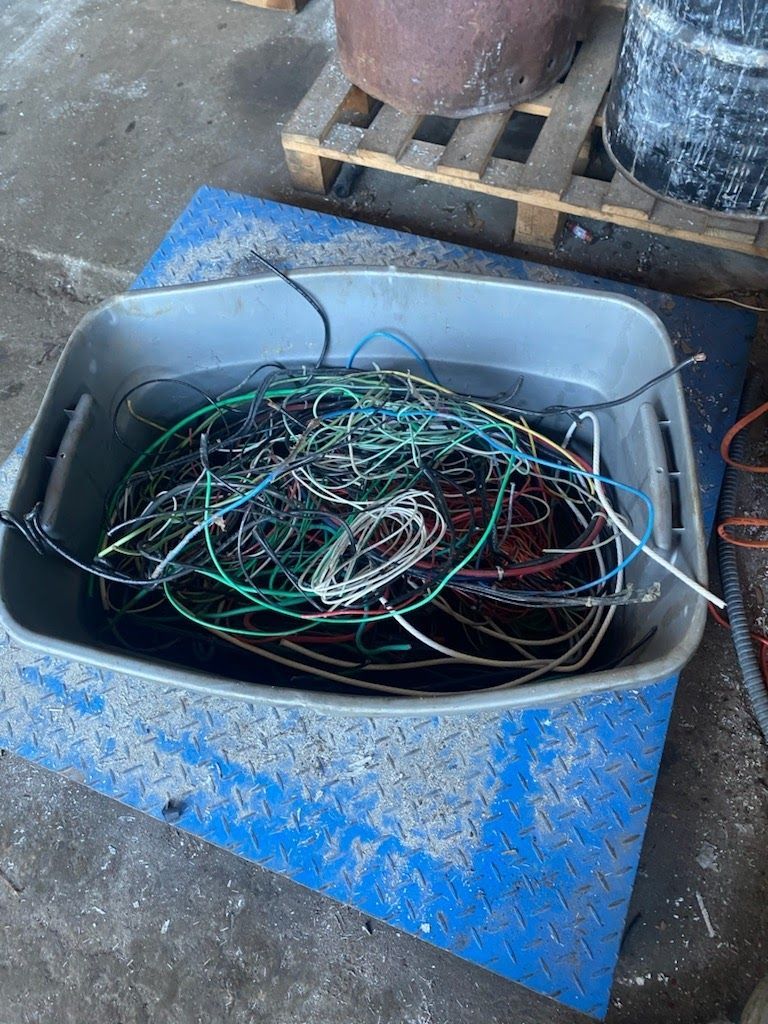 A plastic bin filled with wires is sitting on top of a blue mat.