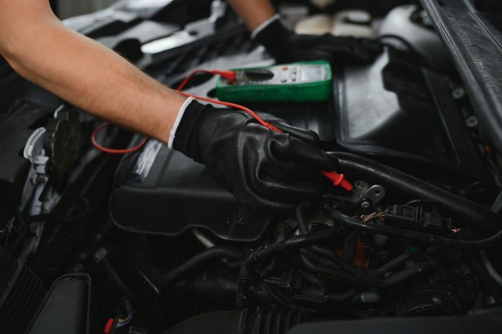 A Man Is Working On A Car Engine With A Multimeter — Evco Automotive in South Albury, NSW