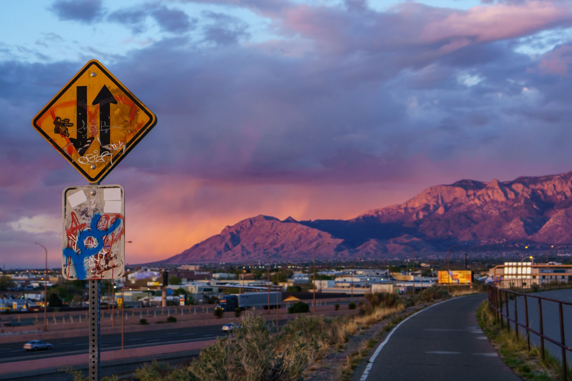 A road with a sign on it and a mountain in the background.