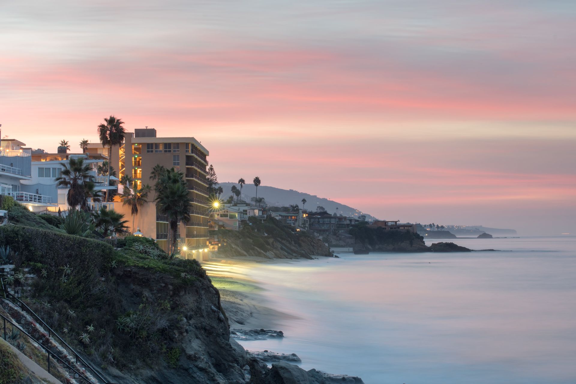 A city on a cliff overlooking the ocean at sunset.