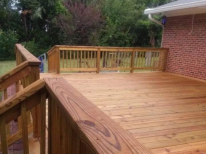 Wooden deck with railings, attached to a brick house. The deck is stained a warm brown color.