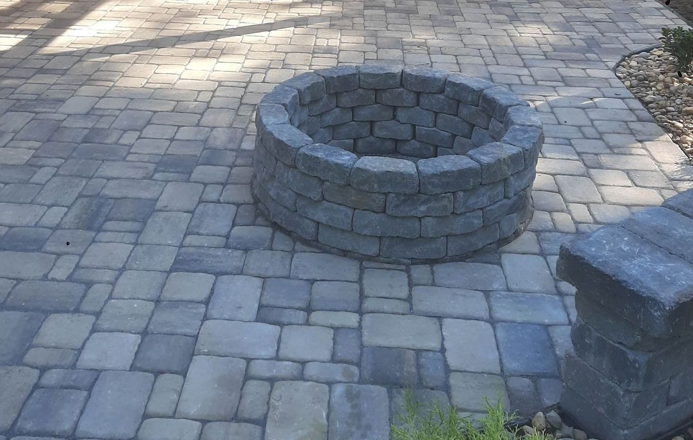 A fire pit is sitting on a brick patio.