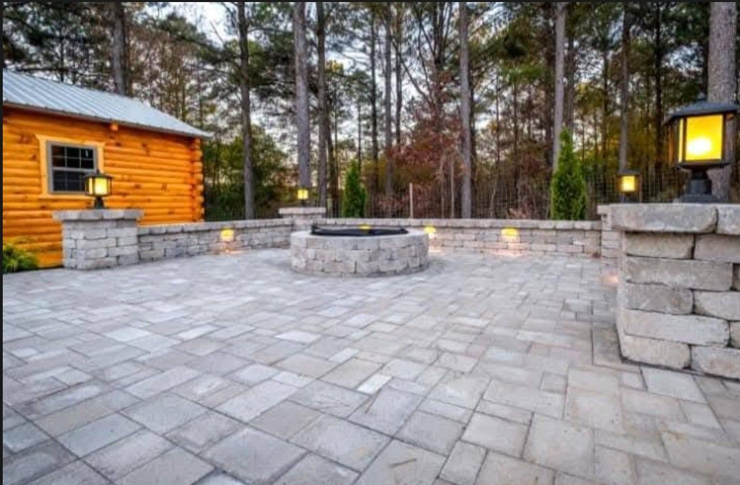 A patio with a fire pit and a log cabin in the background