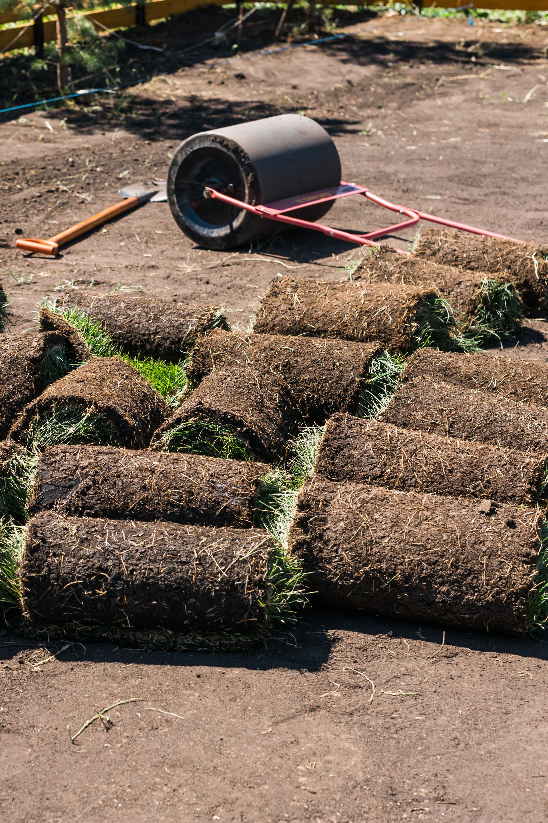 A wheelbarrow is sitting on top of a pile of turf rolls.