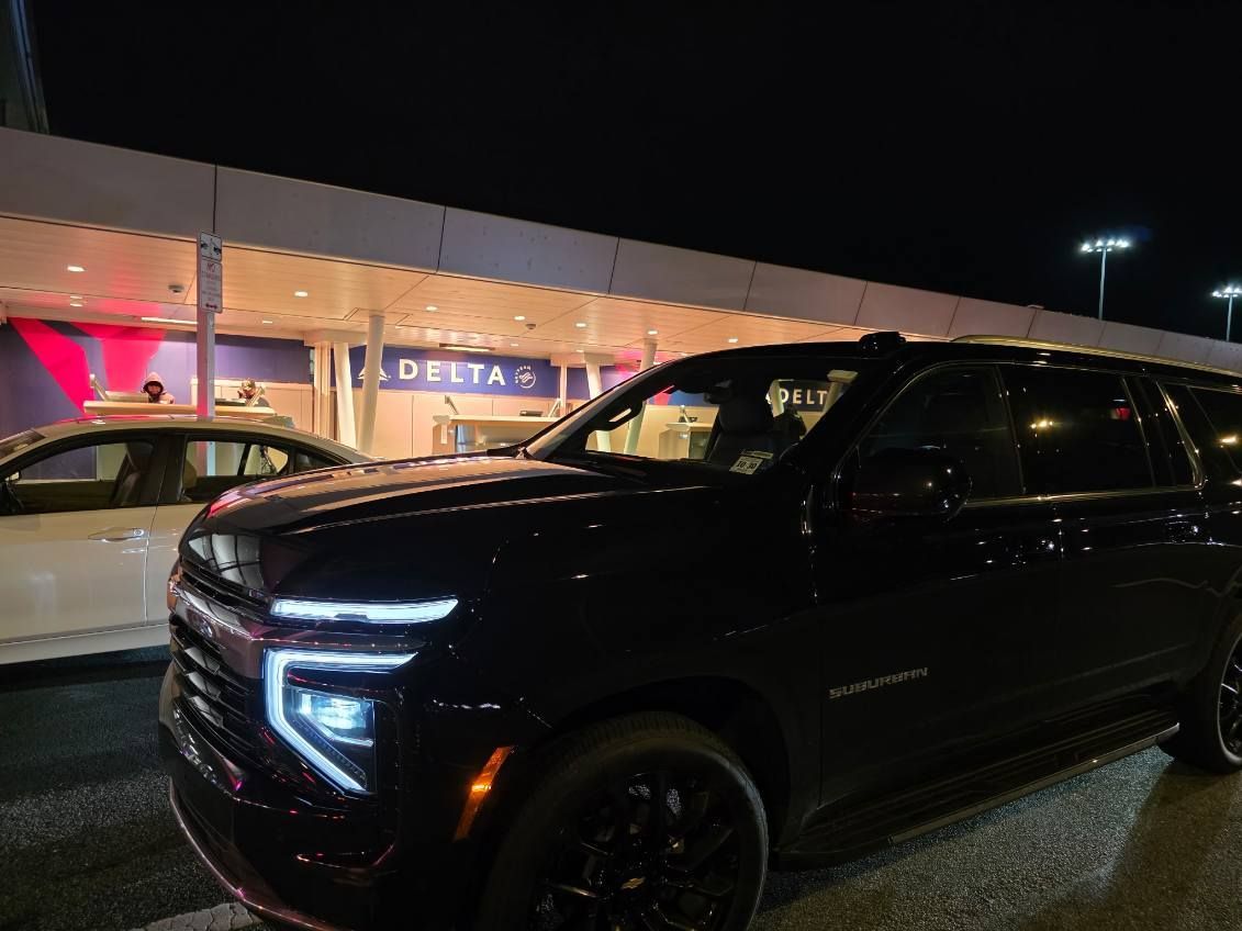 Black SUV parked at a Delta terminal entrance at night.