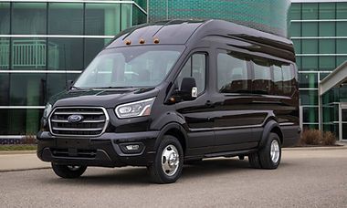 Black Ford Transit passenger van parked in front of a building.
