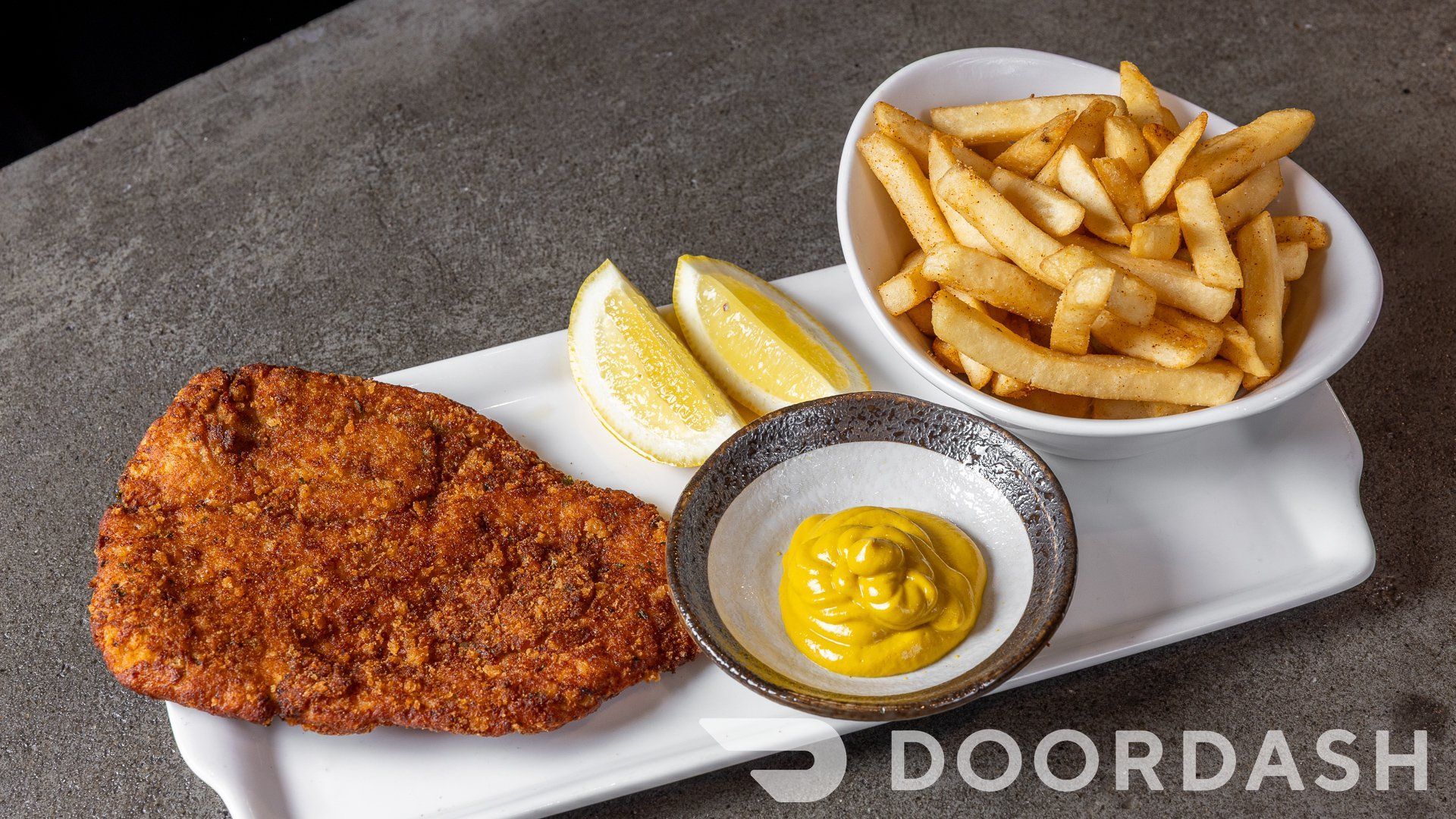 A plate of food with a bowl of french fries and a bowl of mustard.