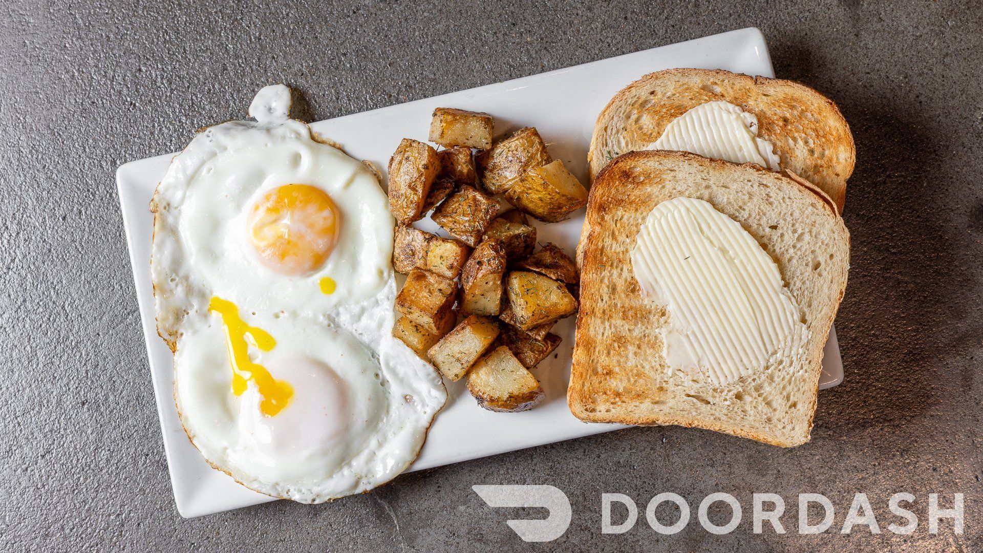 A white plate topped with eggs , potatoes and toast.