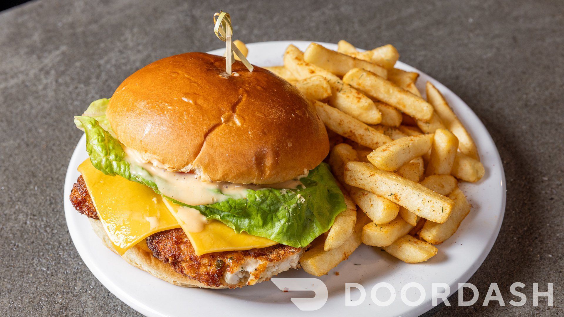 A chicken sandwich and french fries on a white plate.