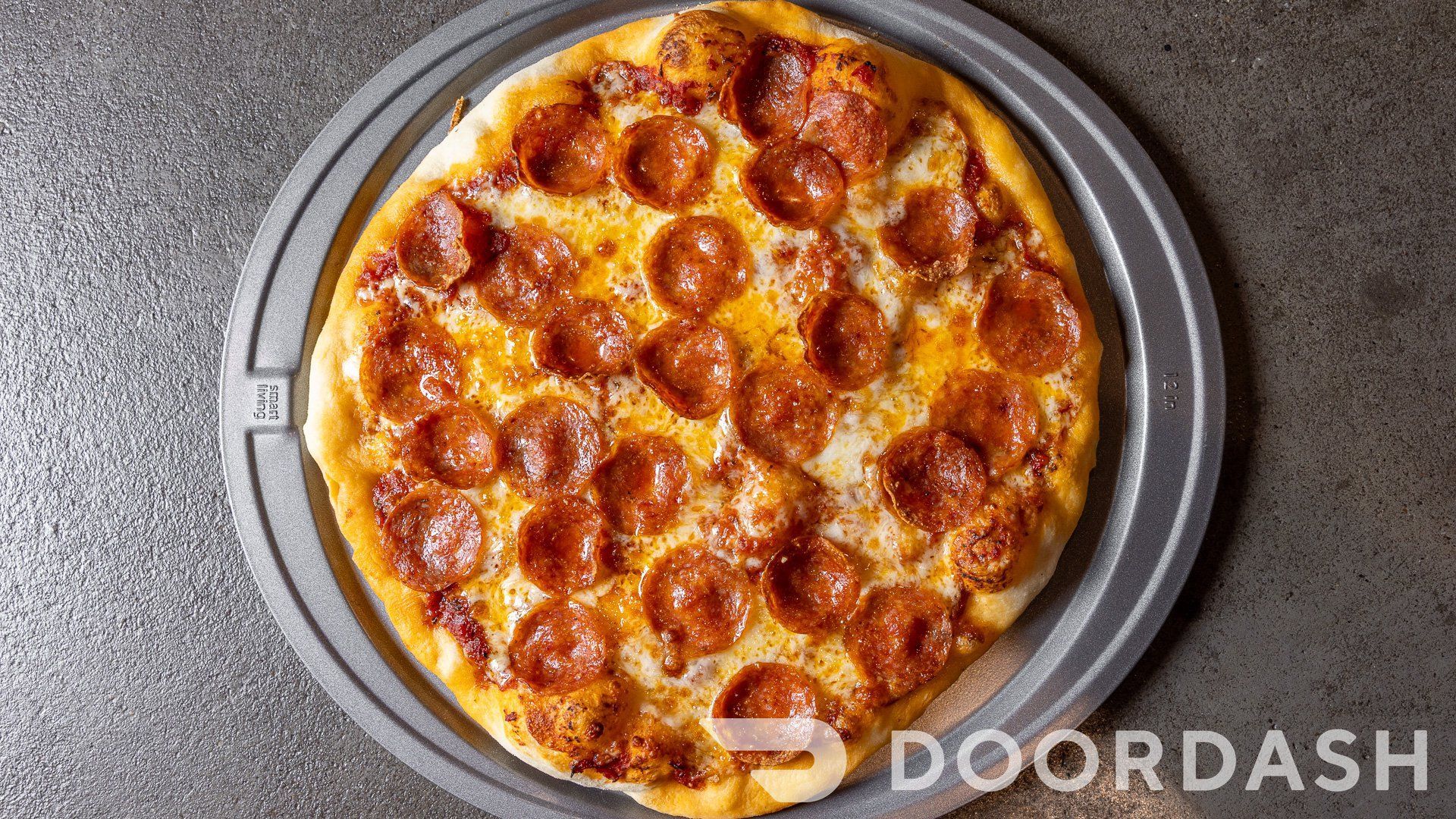 A pepperoni pizza is sitting on a metal pan on a table.