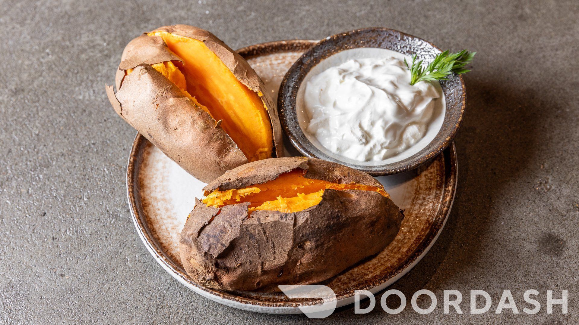 A baked sweet potato with sour cream on a plate.