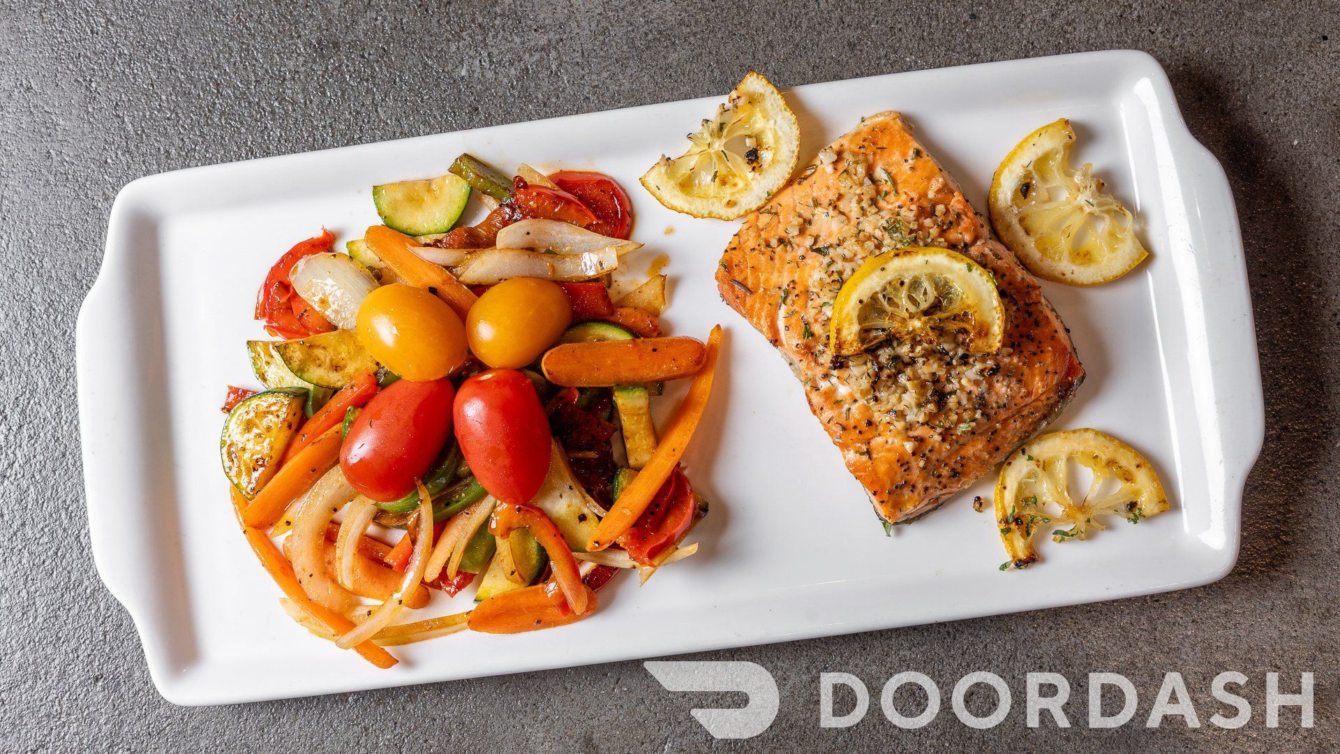 A white plate topped with salmon and vegetables from doordash
