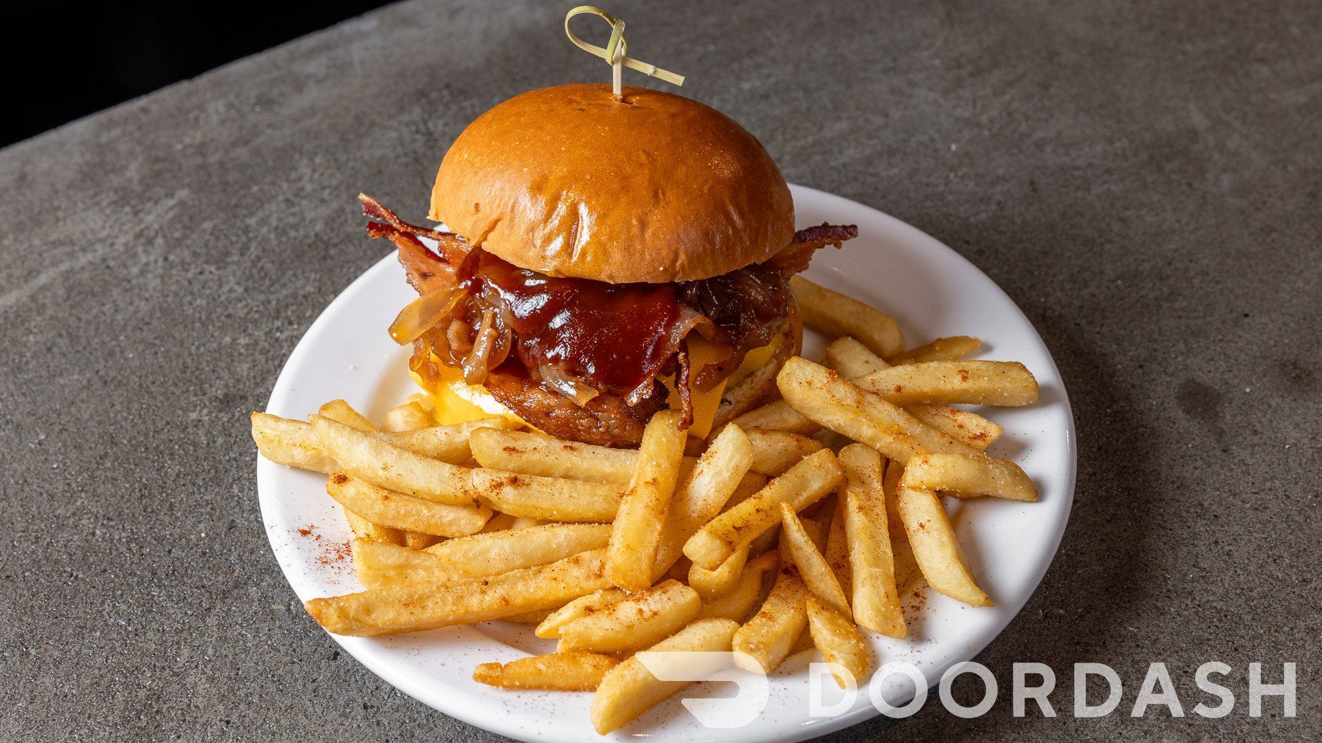 A hamburger and french fries on a white plate on a table.