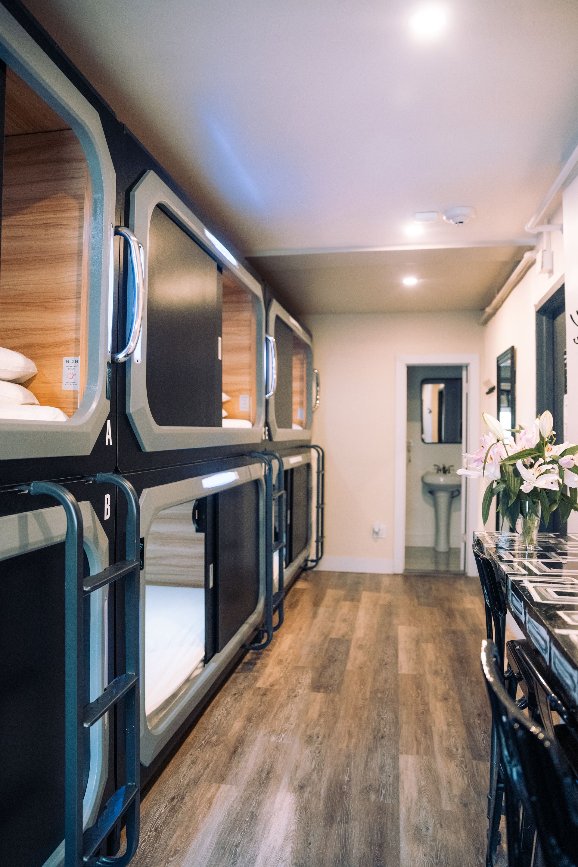 A row of bunk beds in a room with a table and chairs