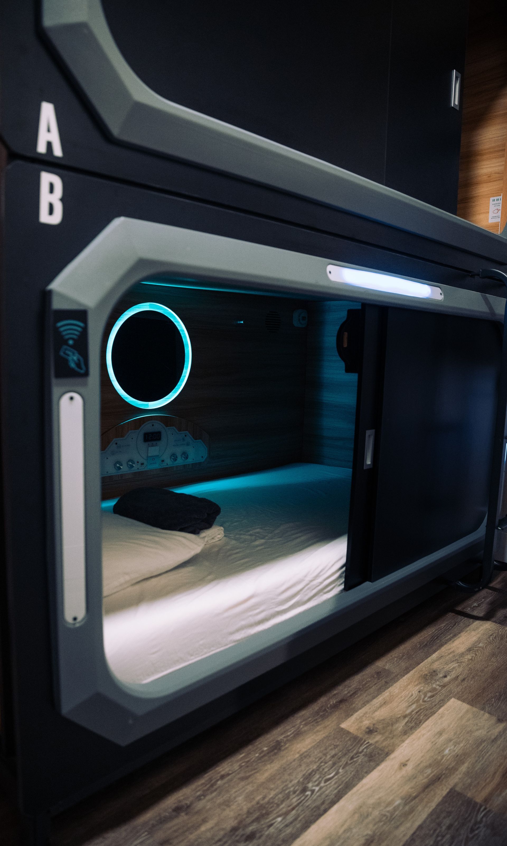 A sleeping pod with a bed in it is sitting on a wooden floor.