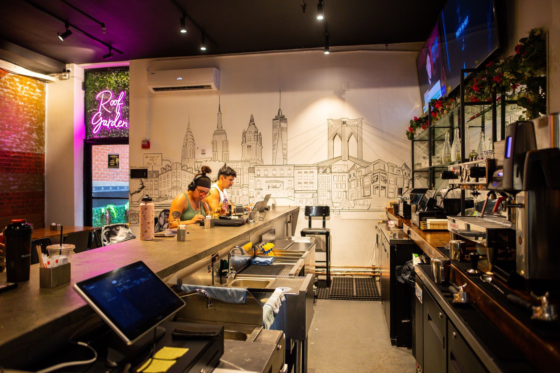 A couple of people are sitting at a long counter in a restaurant.