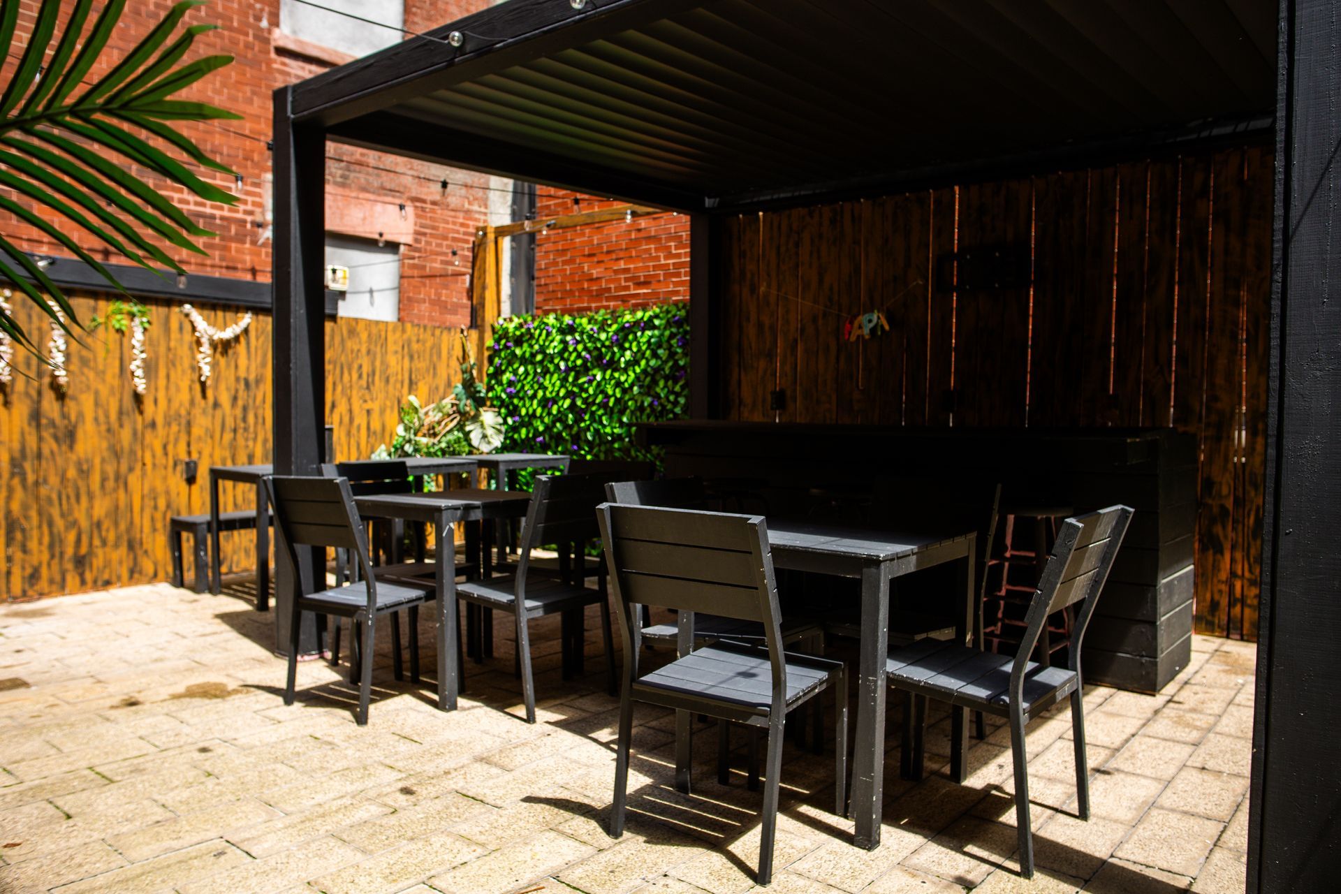 A patio with tables and chairs under a pergola.