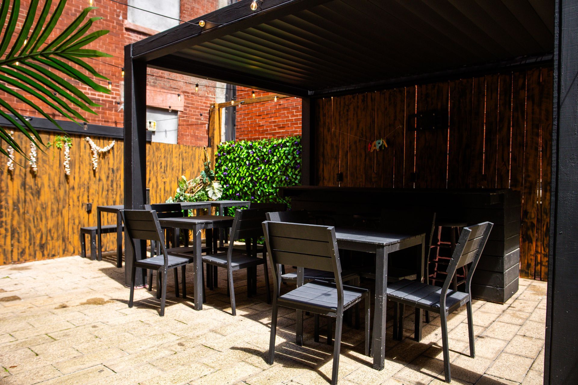A patio with tables and chairs under a pergola.