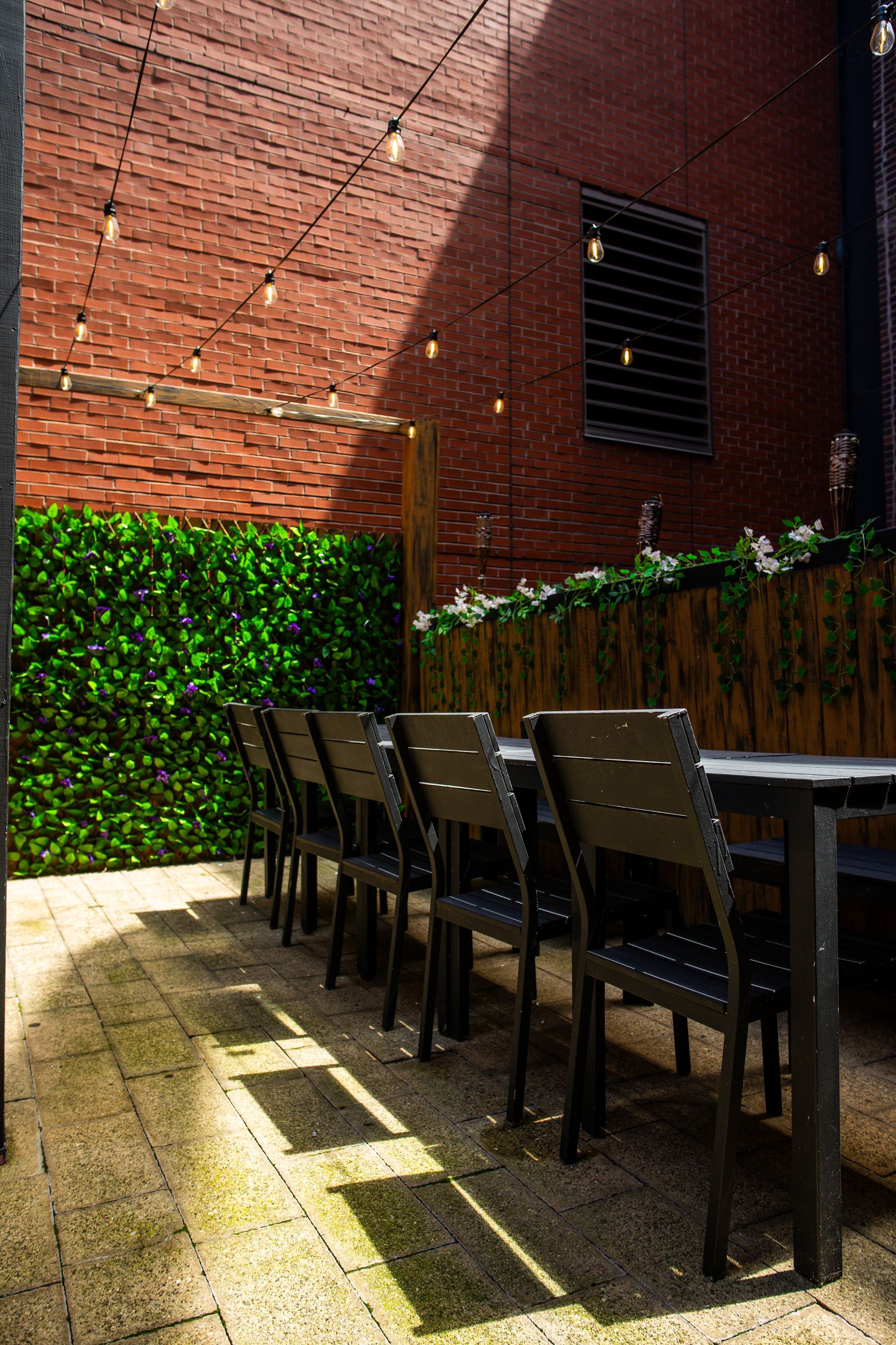 A patio with tables and chairs in front of a brick wall