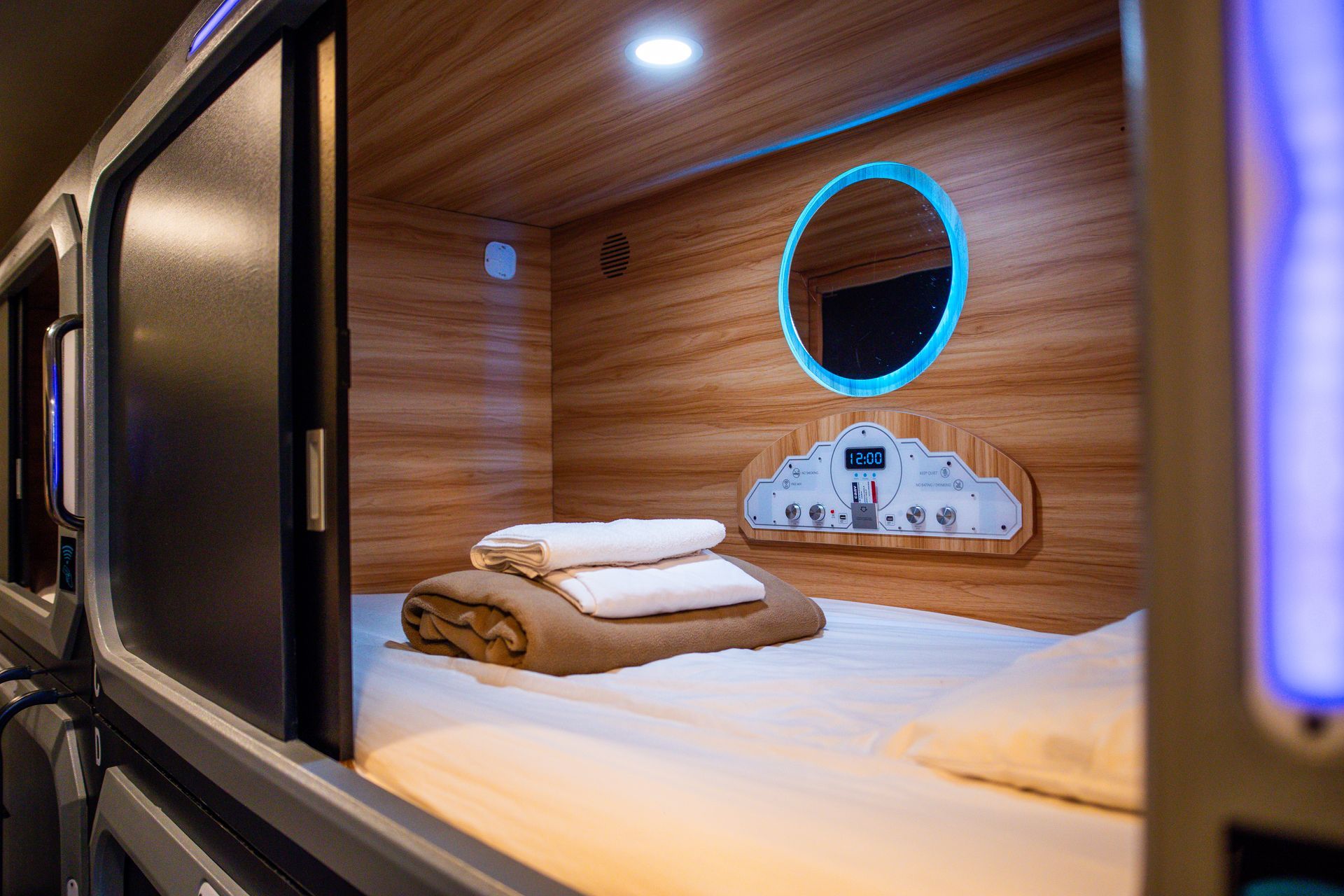 A capsule hotel room with a bed and a mirror.